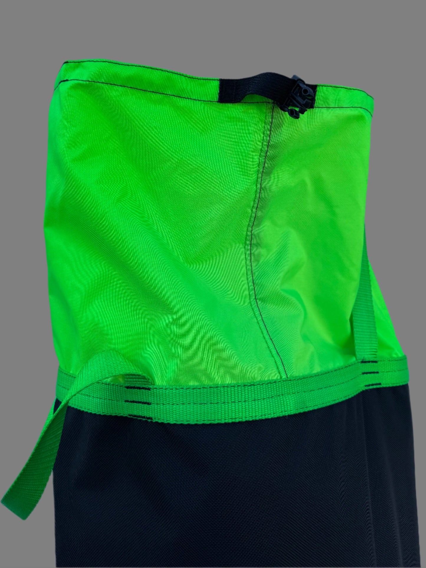 Green and black bag with a strap on a white surface
